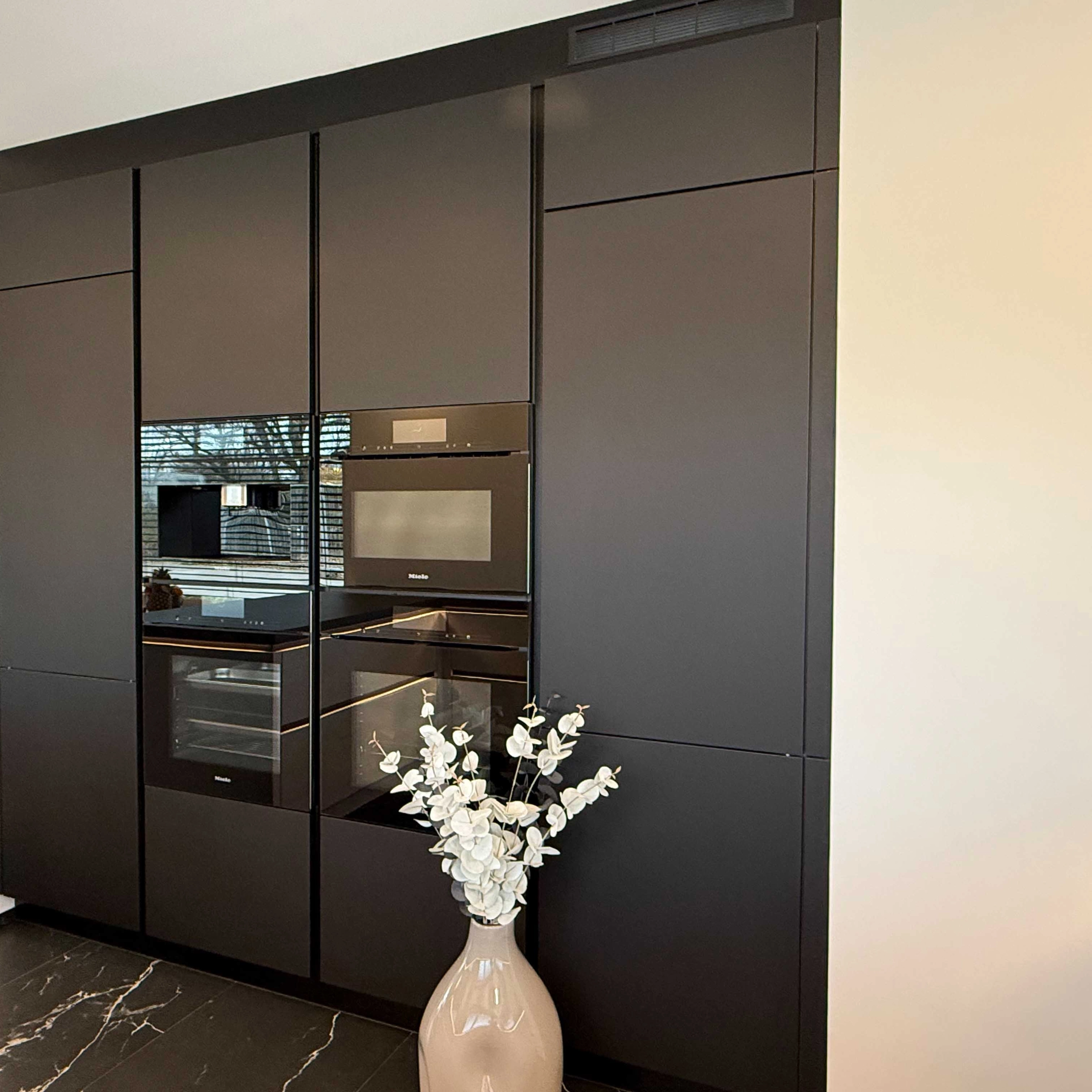 Cuisine intégrée moderne noire avec bouquet de fleurs blanches, Nolte Kitchen.