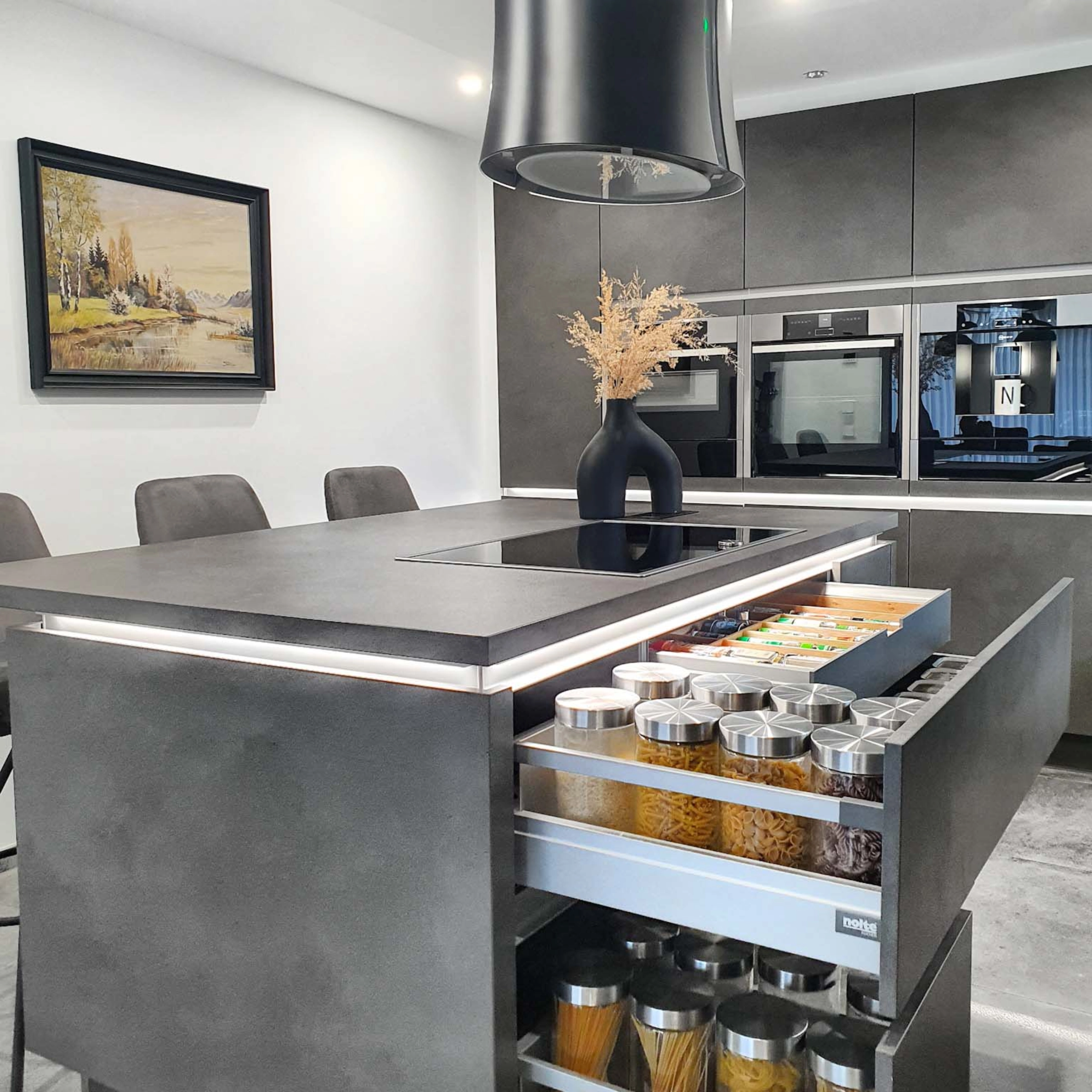 Cuisine moderne avec armoires grises et îlot, conçue par Nolte Kitchen.