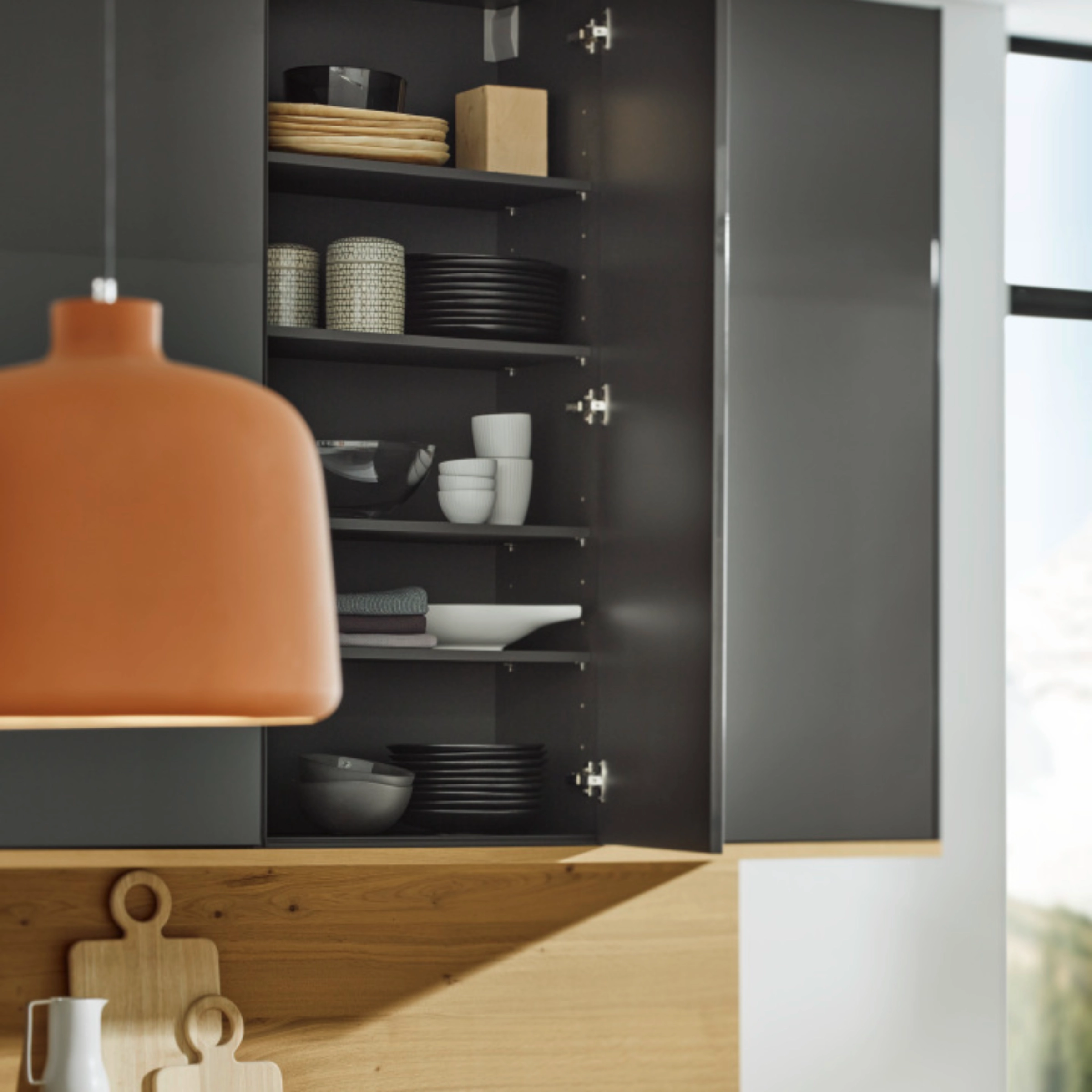 Une cuisine moderne avec armoire ouverte montrant vaisselle et accessoires en bois, Nolte Kitchen.