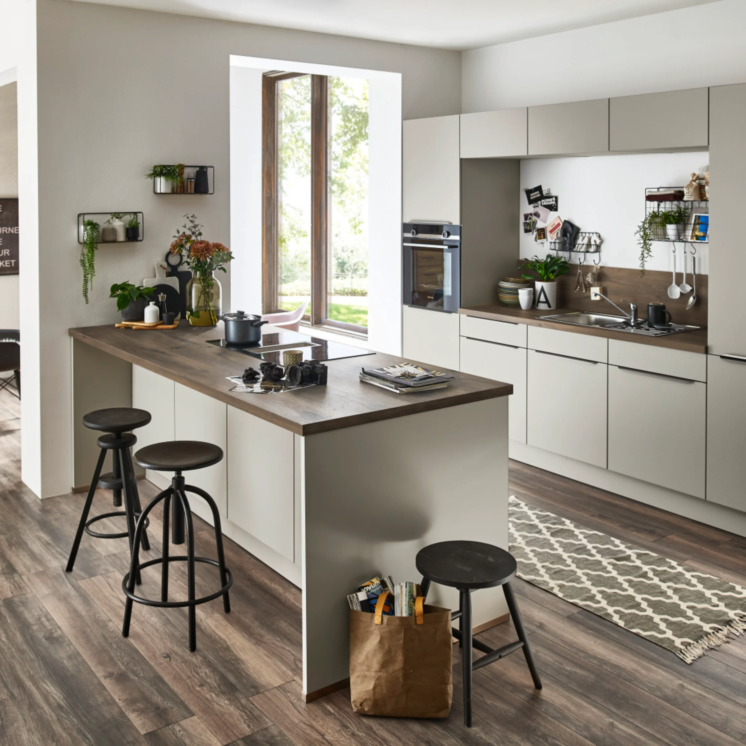 Moderne Küche mit Kücheninsel, Barhockern und Holzfußboden, gestaltet von Nolte Küchen.