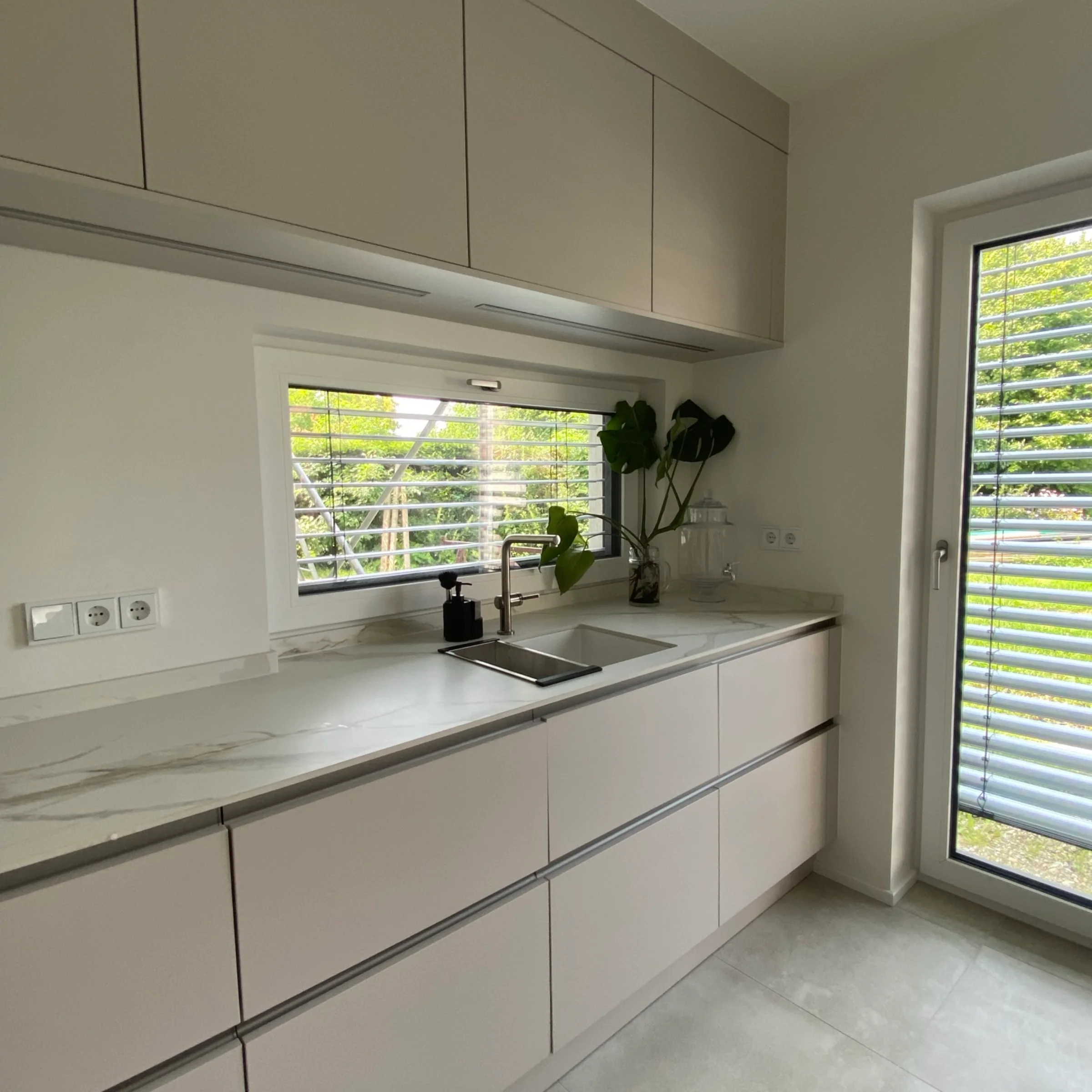 Nowoczesna kuchnia o eleganckim designie z dużymi oknami. Nolte Küchen.