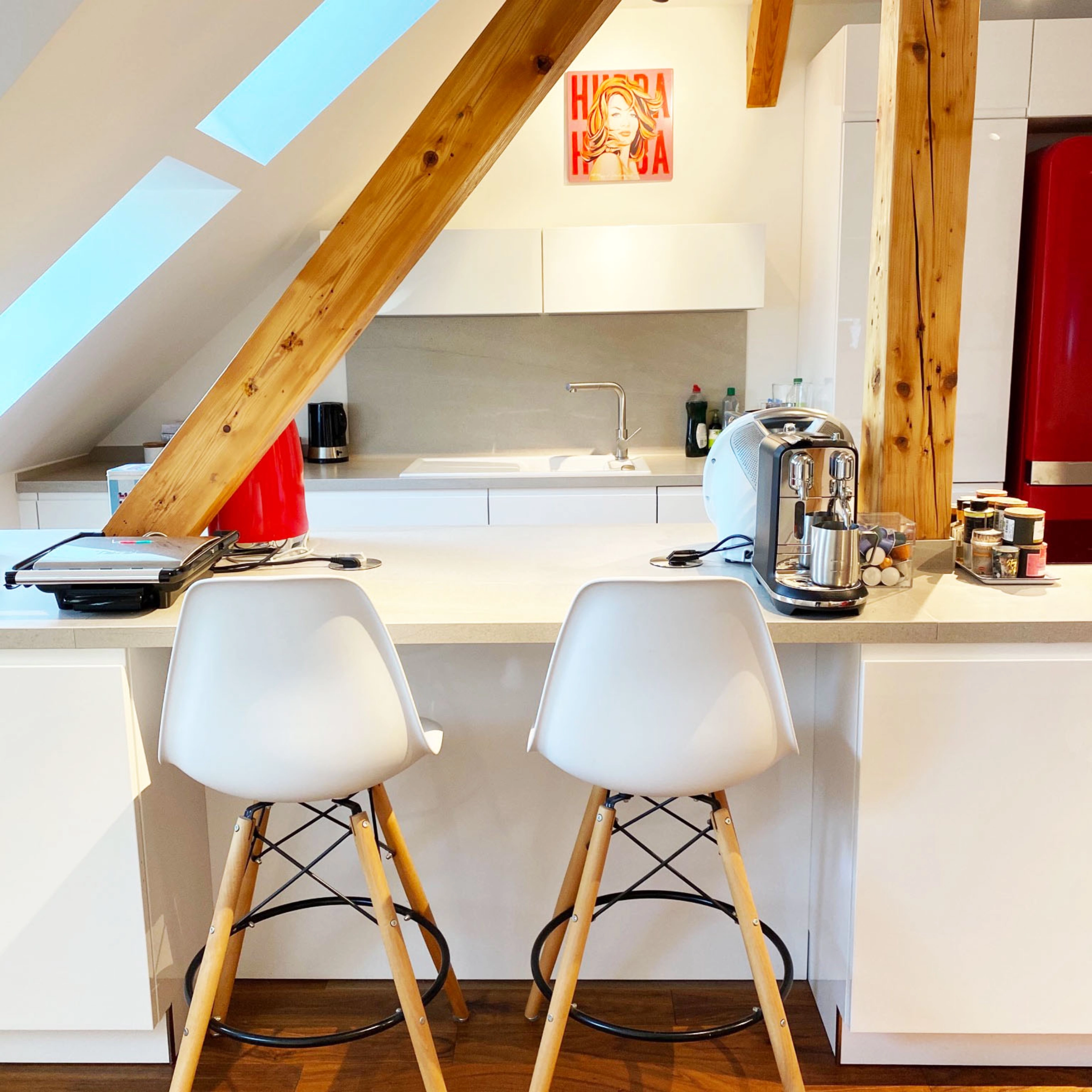 Cuisine moderne avec armoires blanches et détails en bois, équipée par Nolte Kitchen.