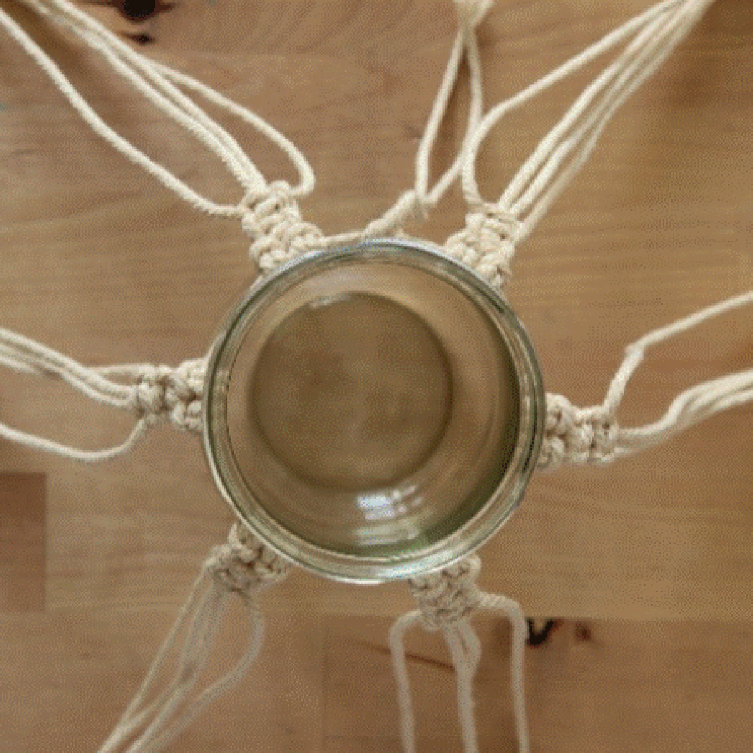 Un vase en verre suspendu dans un filet de macramé artistiquement noué.