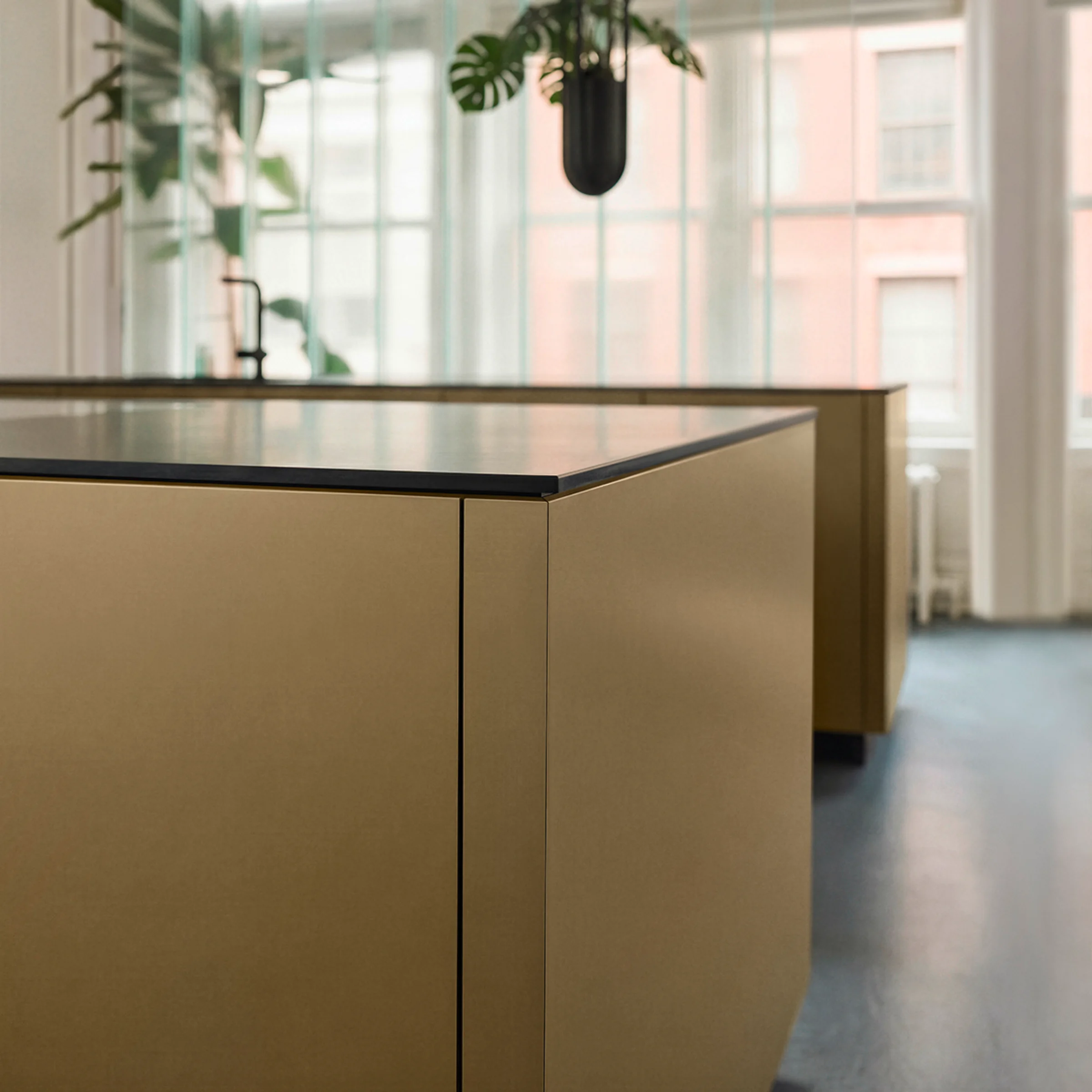 A modern kitchen with large windows and a golden island. Nolte Küchen.