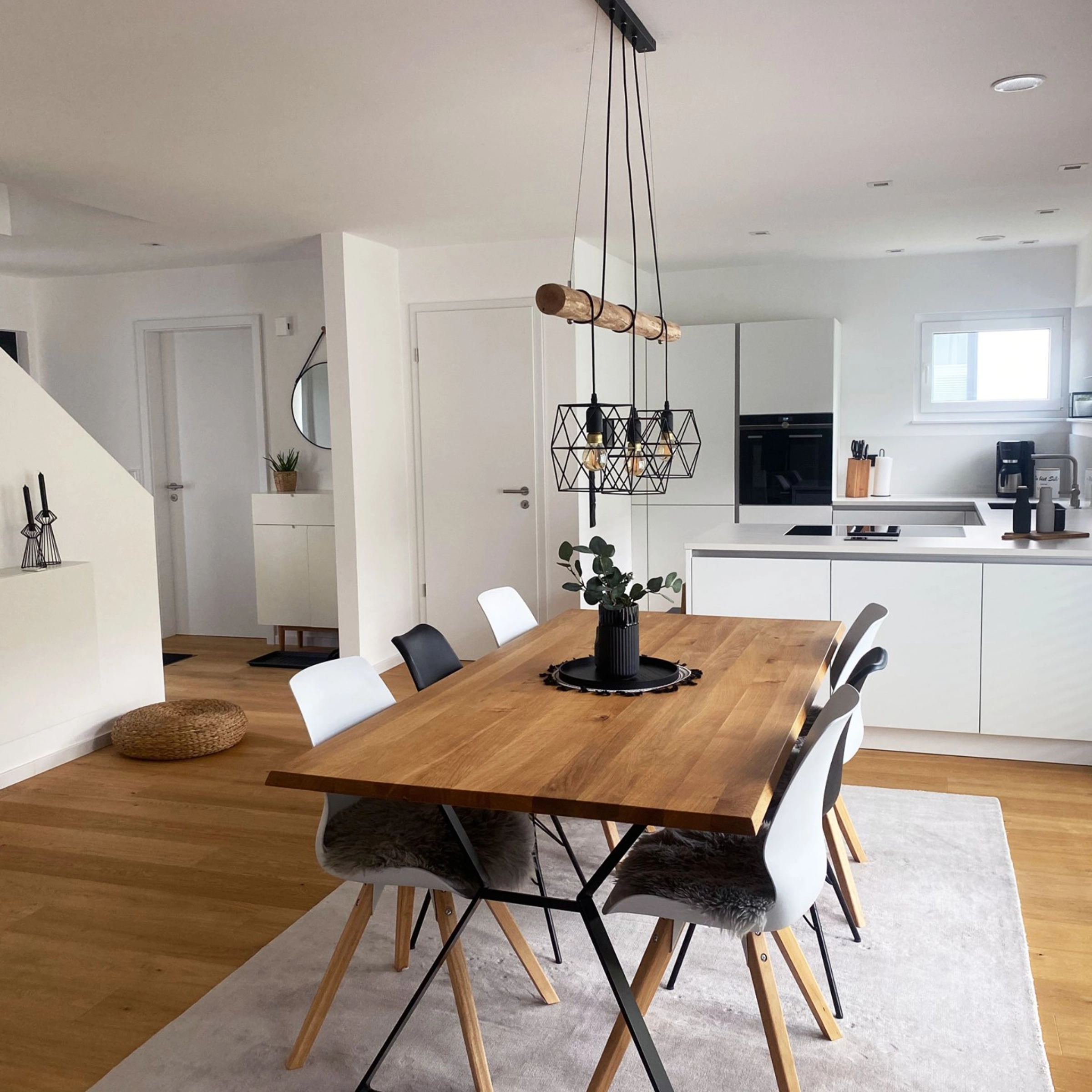 Salle à manger moderne avec table en bois et chaises blanches, à côté d'une cuisine ouverte de Nolte Kitchen.