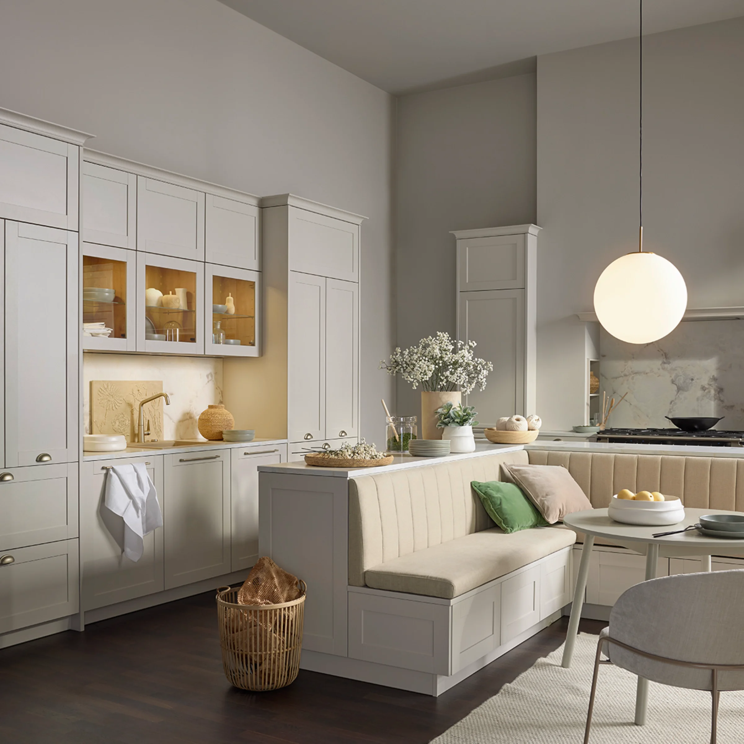Gemütliche Wohnküche im Landhausstil mit heller Sitzbank, runder Leuchte und natürlicher Dekoration. Die Fronten in Sahara-Farbton verleihen der Nolte CHESTER Küche eine zeitlose Eleganz.