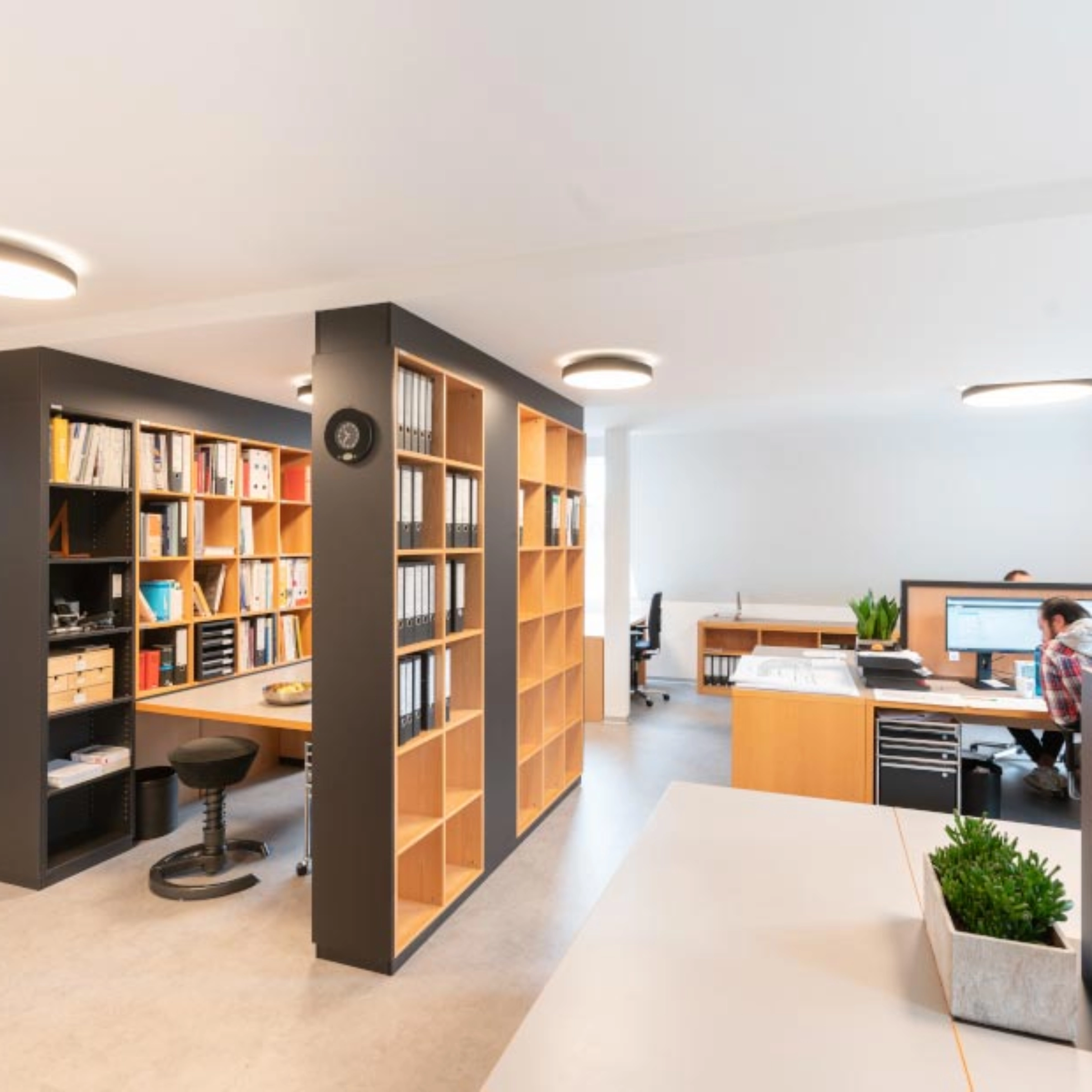 Un bureau moderne avec étagères et bureaux créant un environnement de travail organisé.