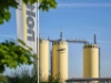 Drei gelbe Silos mit dem Logo von Nolte Küchen vor blauem Himmel.