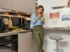 A woman stands in a modern Nolte kitchen, drinking a green smoothie.