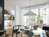 Un espace de vie lumineux avec table à manger et kitchenette, entouré de plantes, présente Nolte Living.