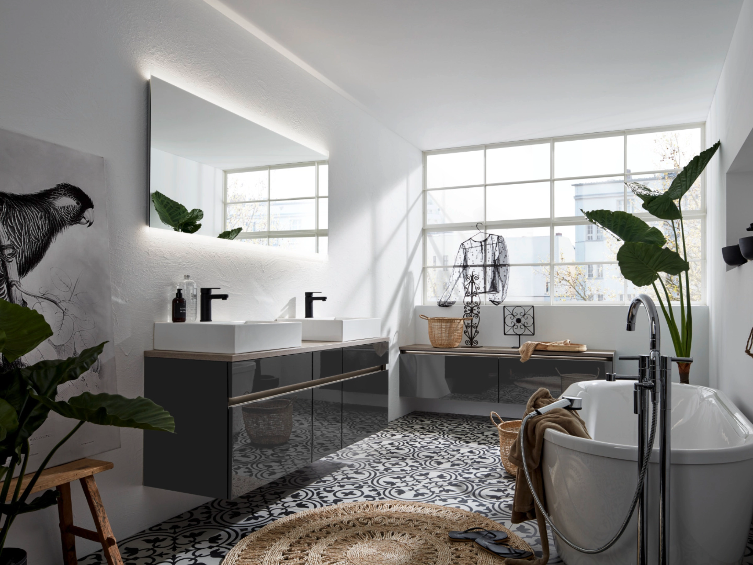 Een modern badkamer met bad en dubbele wastafel, omringd door planten. Nolte SPA.
