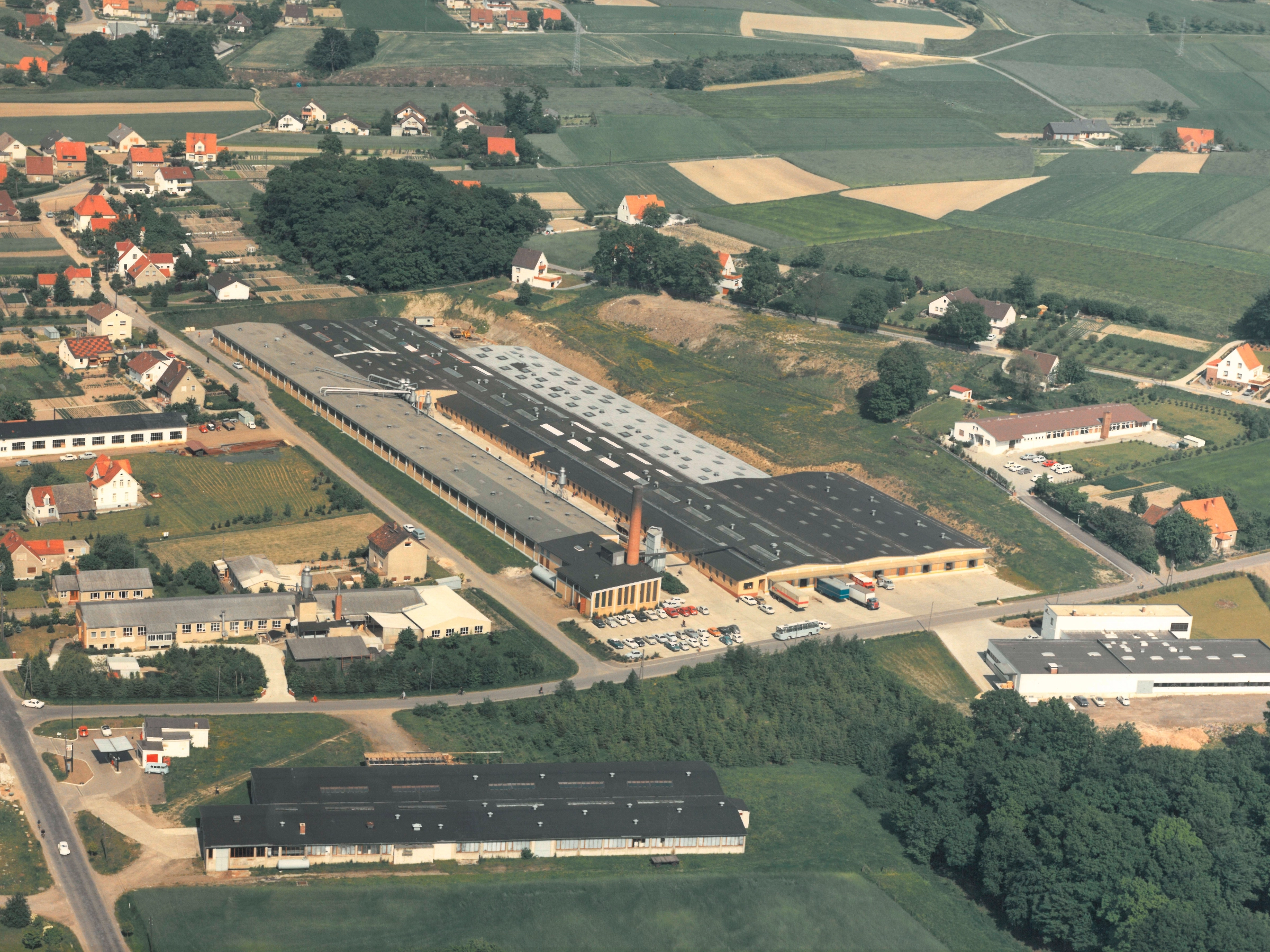 Dans un cadre rural, on voit des bâtiments d'usine Nolte entourés de champs et de petites localités.