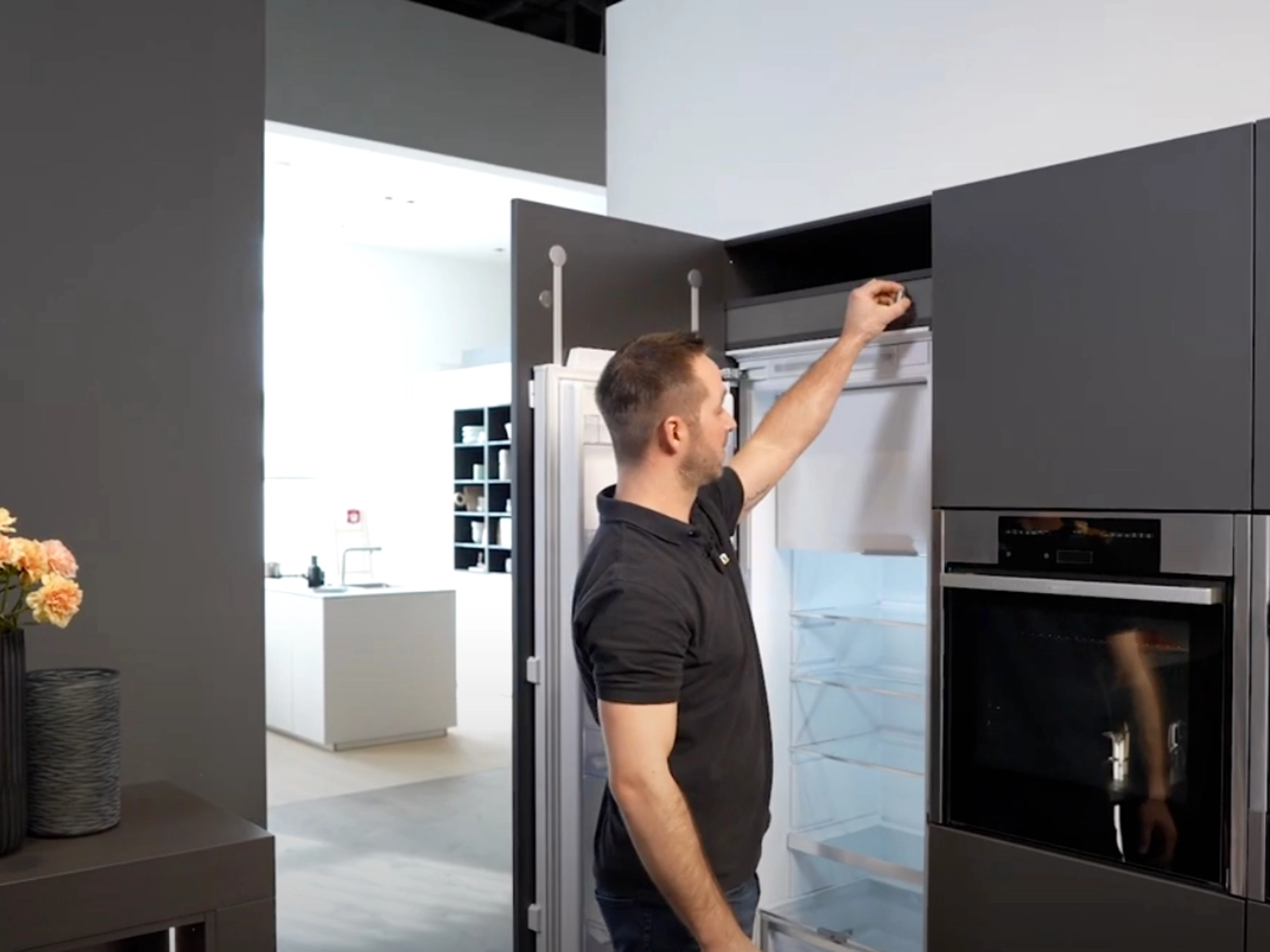 A man opens a refrigerator in a modern Nolte Kitchen kitchen.