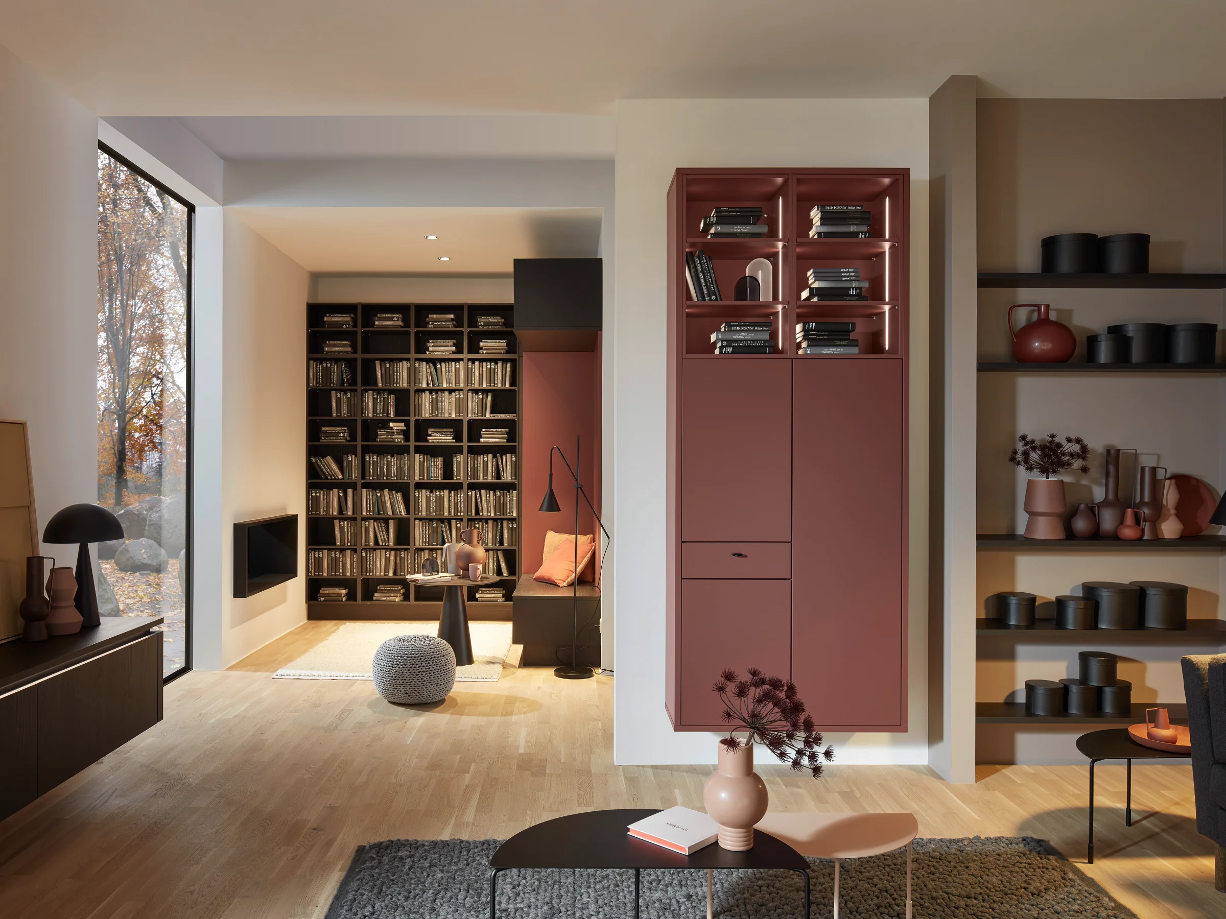 Ein modernes Wohnzimmer mit Regalen und gemütlicher Sitzecke, integriert in Nolte Living.