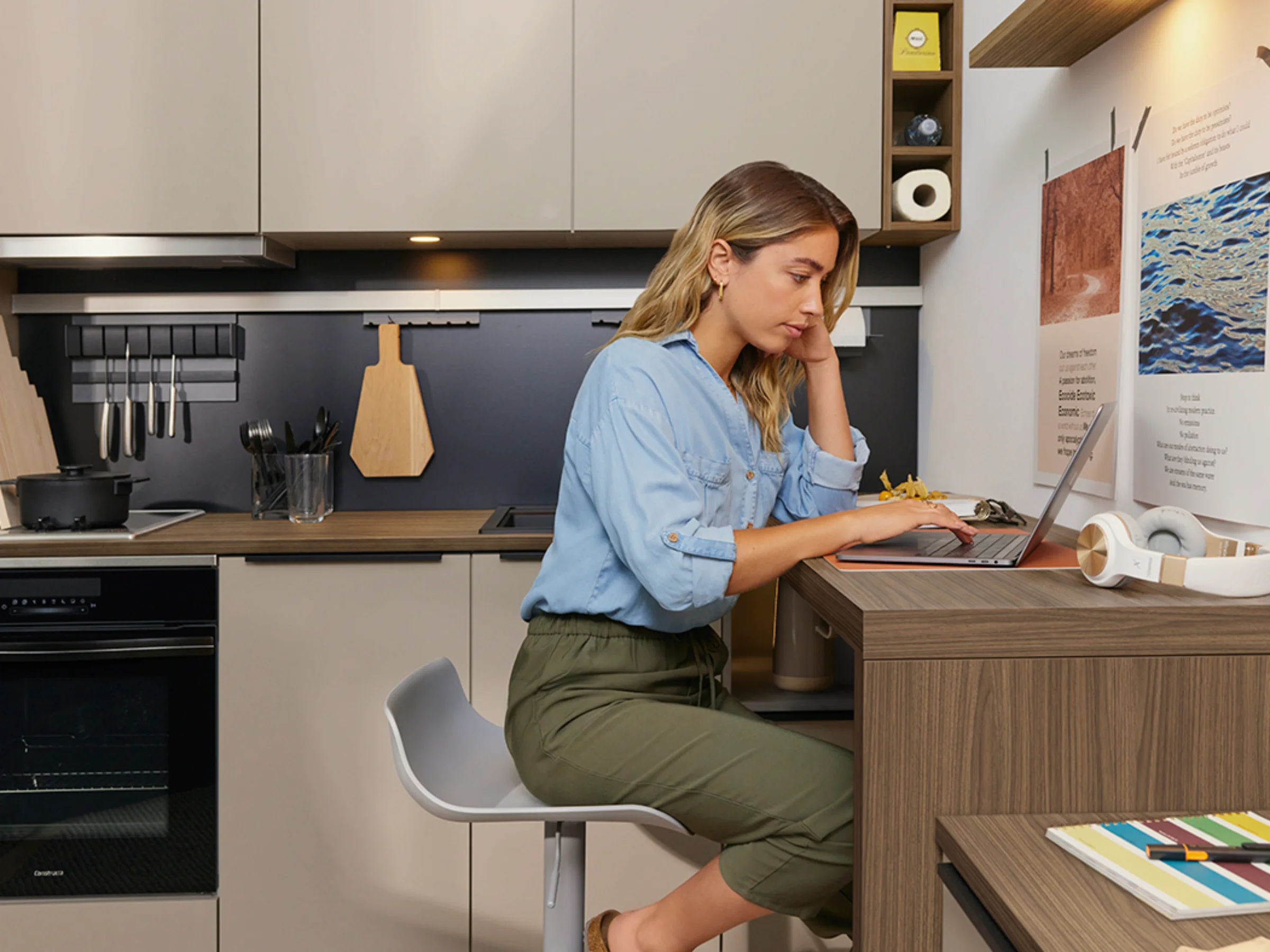 Een vrouw werkt in een moderne keuken met Nolte-keukens op haar laptop.