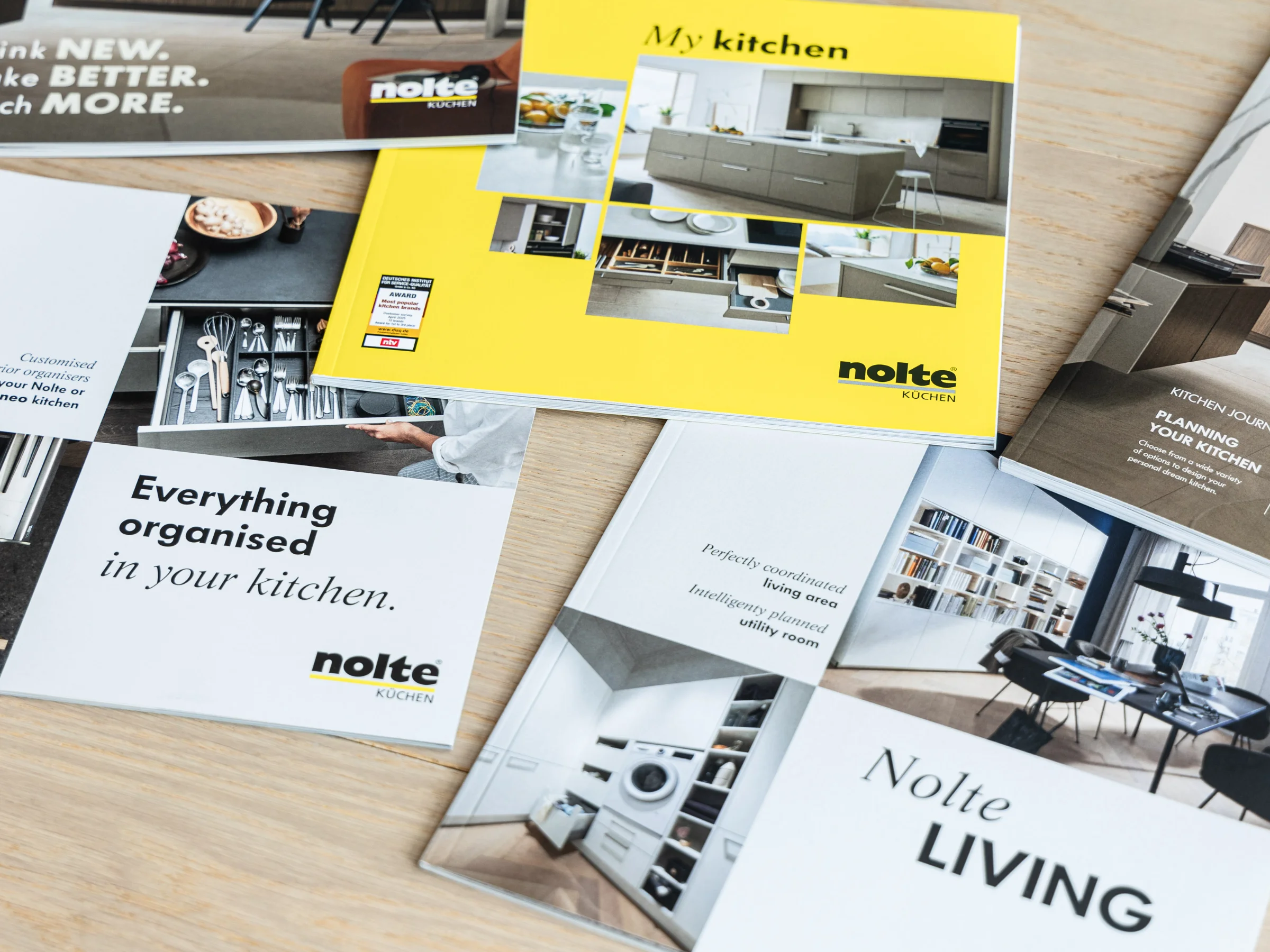 Quatre brochures sur Nolte Kitchen, Nolte Living et NolteNeo Designs sont posées sur une table.