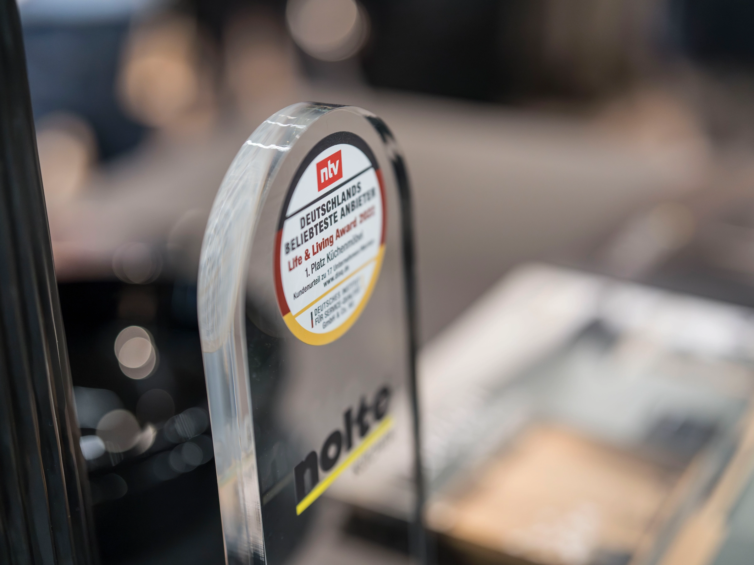 Un trophée en verre avec le logo de Nolte est posé sur une table.