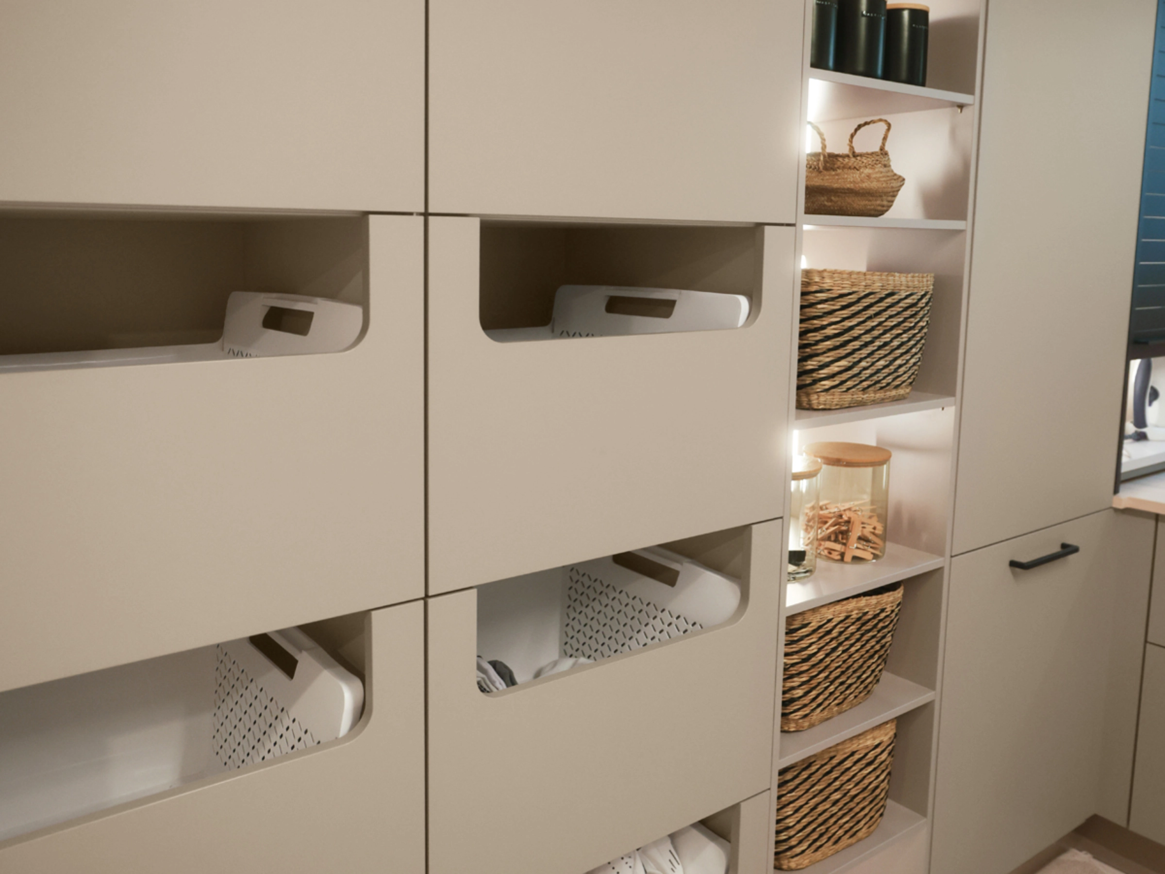 A utility room with beige cabinets and baskets, presented by Nolte Utility Rooms.
