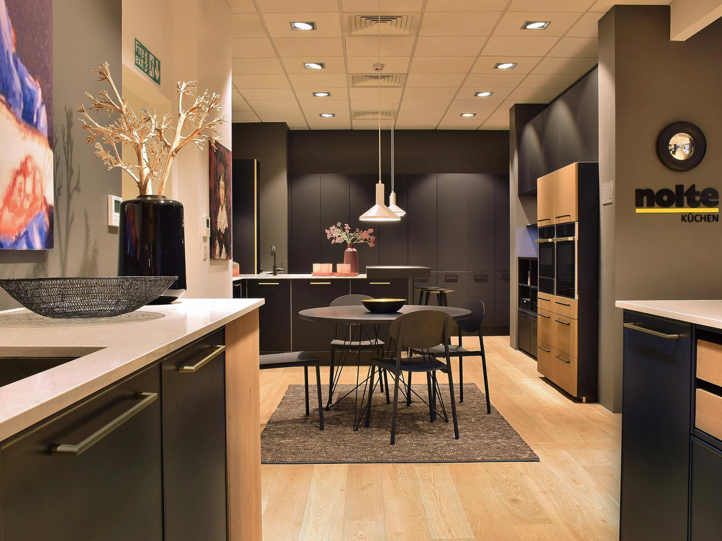 Une cuisine moderne avec table à manger et éclairage de Nolte Kitchen.