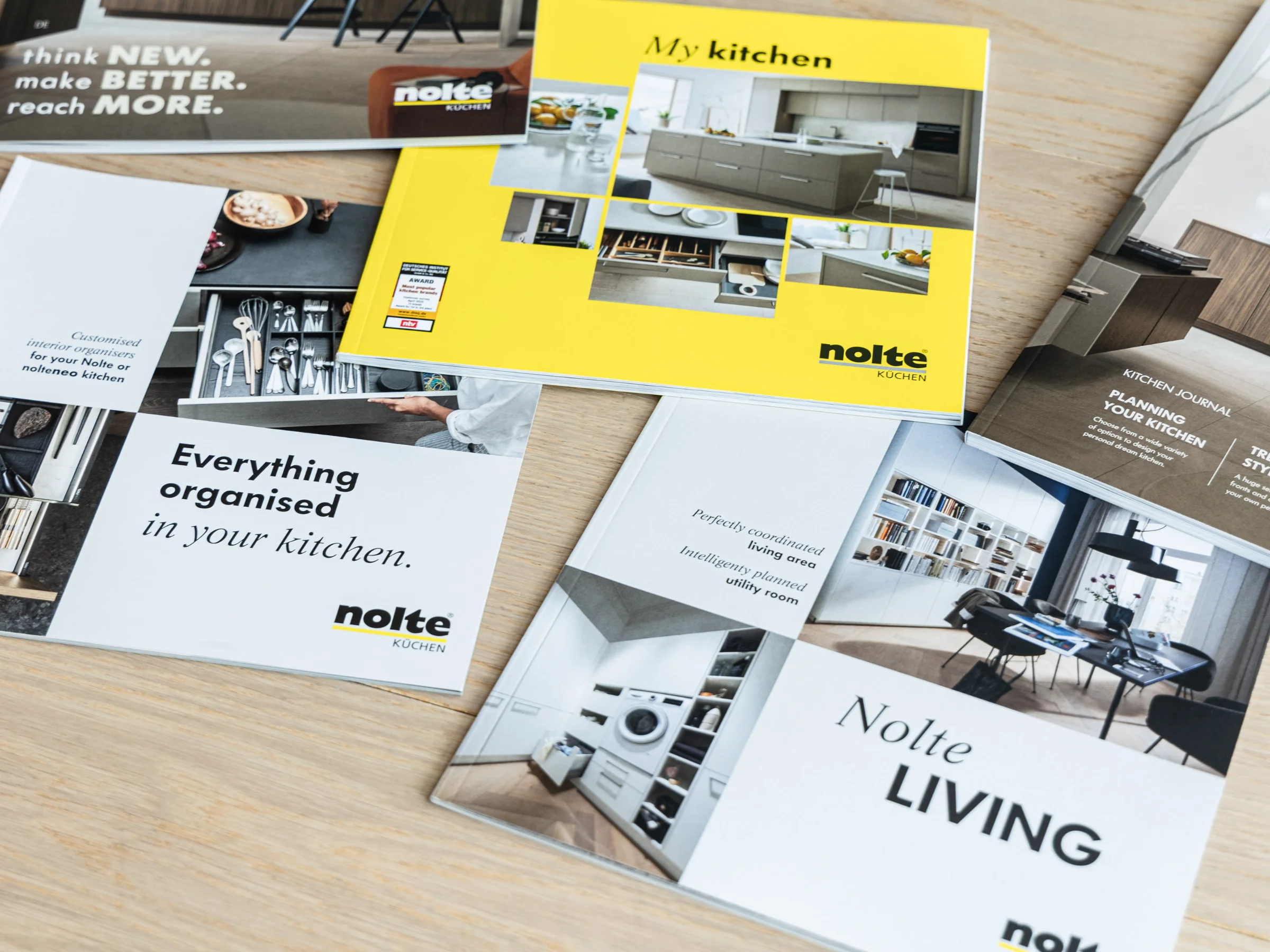 Vier Nolte-keukencatalogi liggen op een grijze ondergrond.