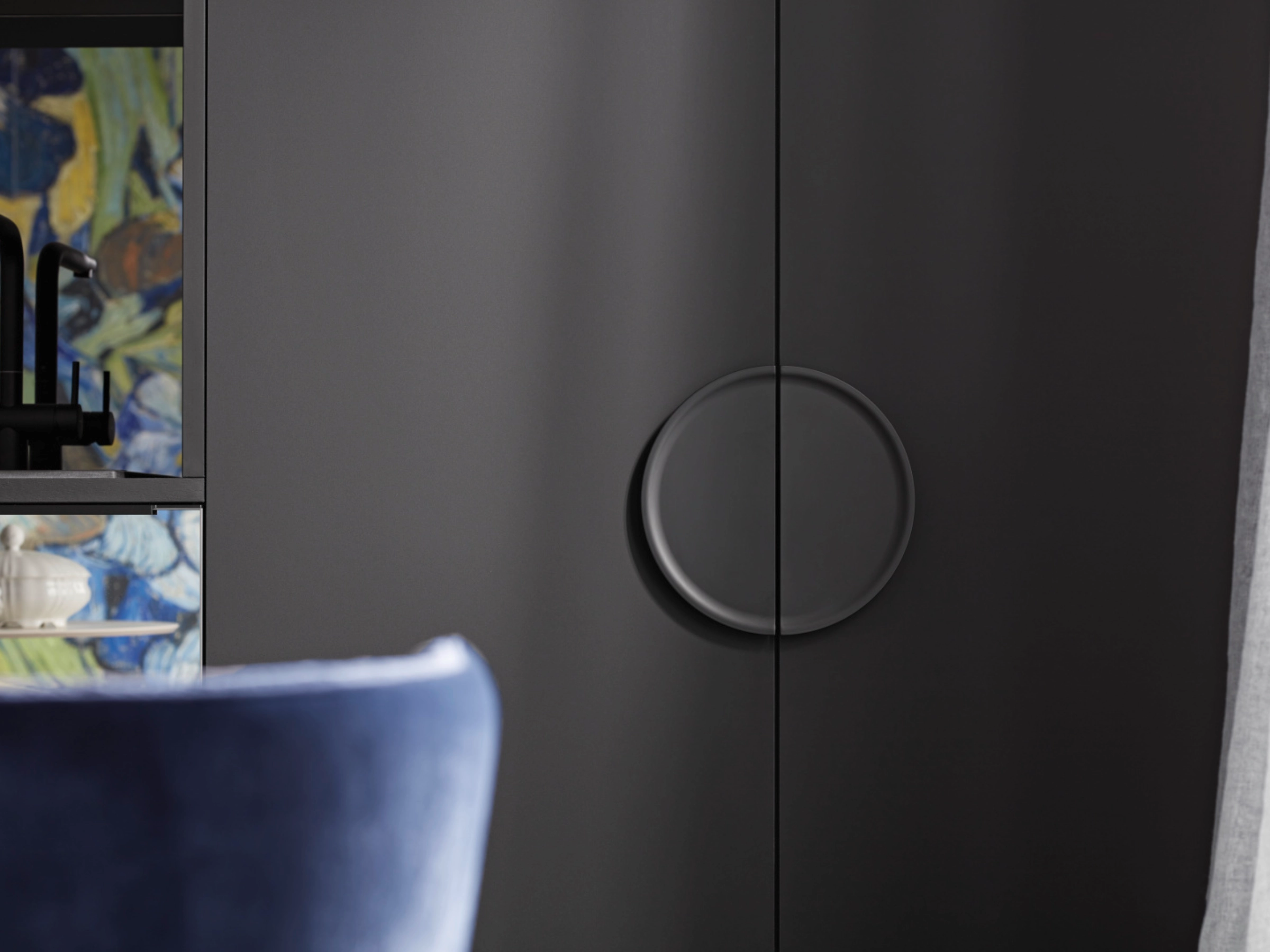 Une élégante armoire avec poignée ronde à côté d'une chaise bleue, de la collection Nolte Living.