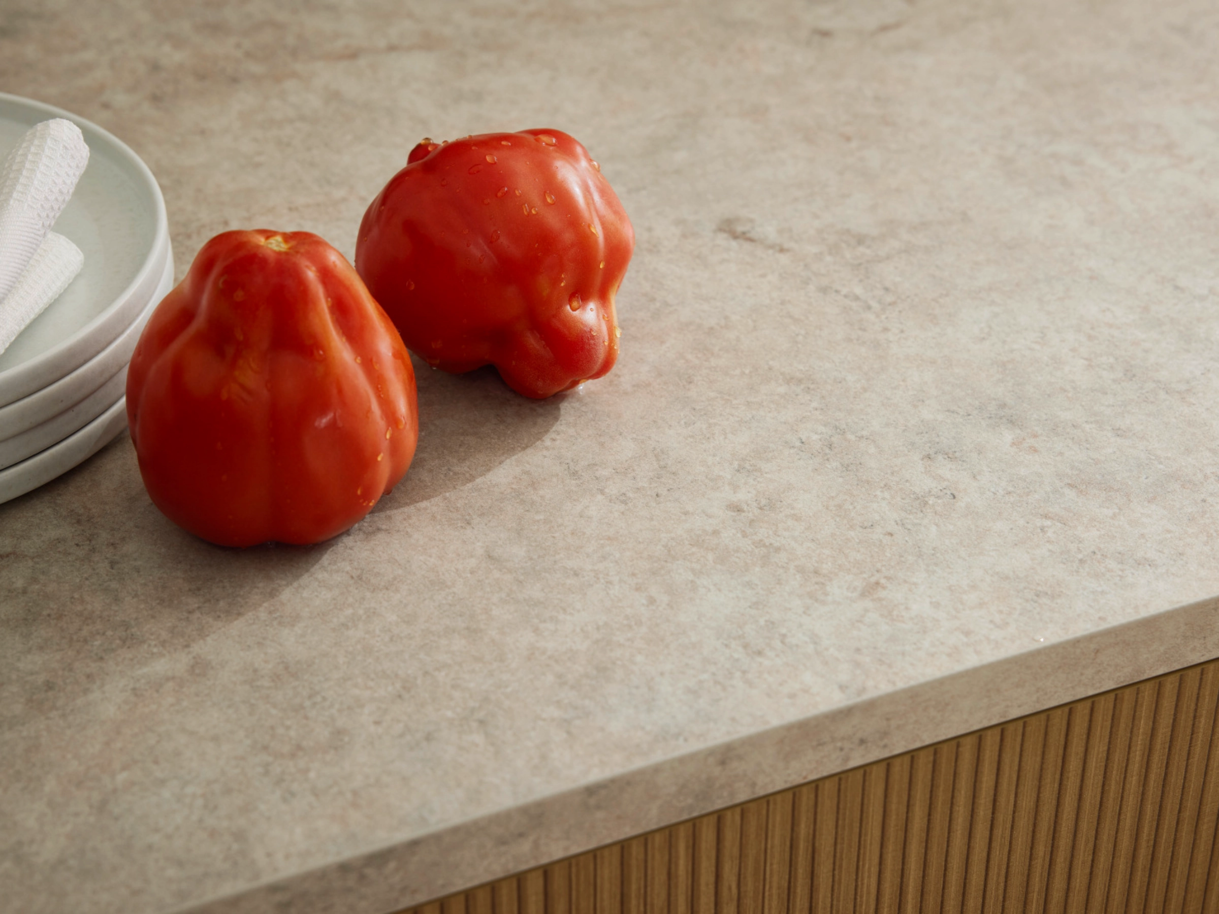 Deux poivrons rouges et une assiette sur un plan de travail dans une cuisine Nolte.