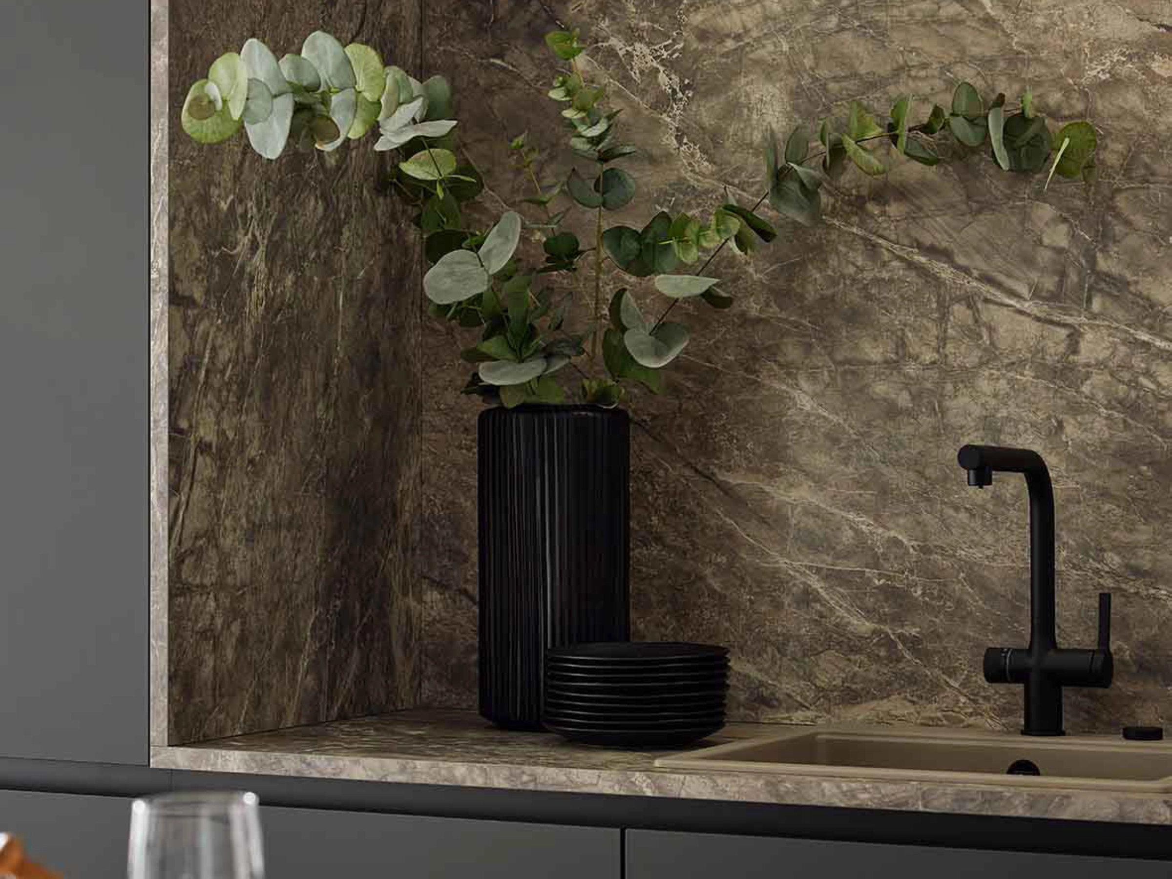 Une cuisine élégante avec effet marbre et robinet noir, agrémentée de plantes vertes. Nolte Kitchen.
