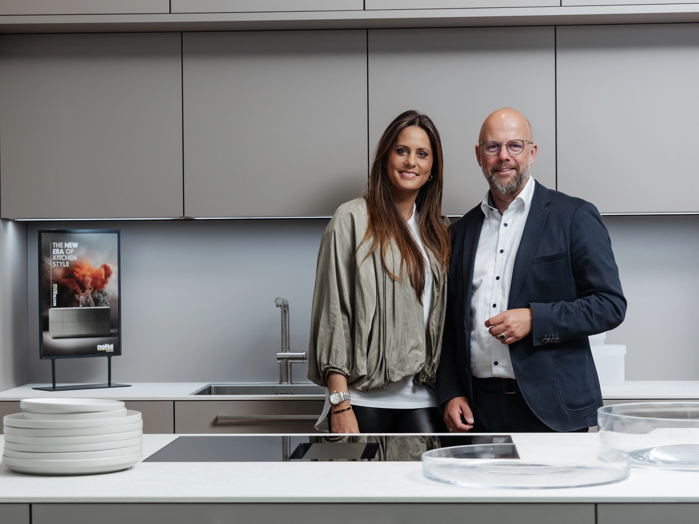 Un couple se tient dans une cuisine moderne avec îlot et design intégré de Nolte Kitchen.