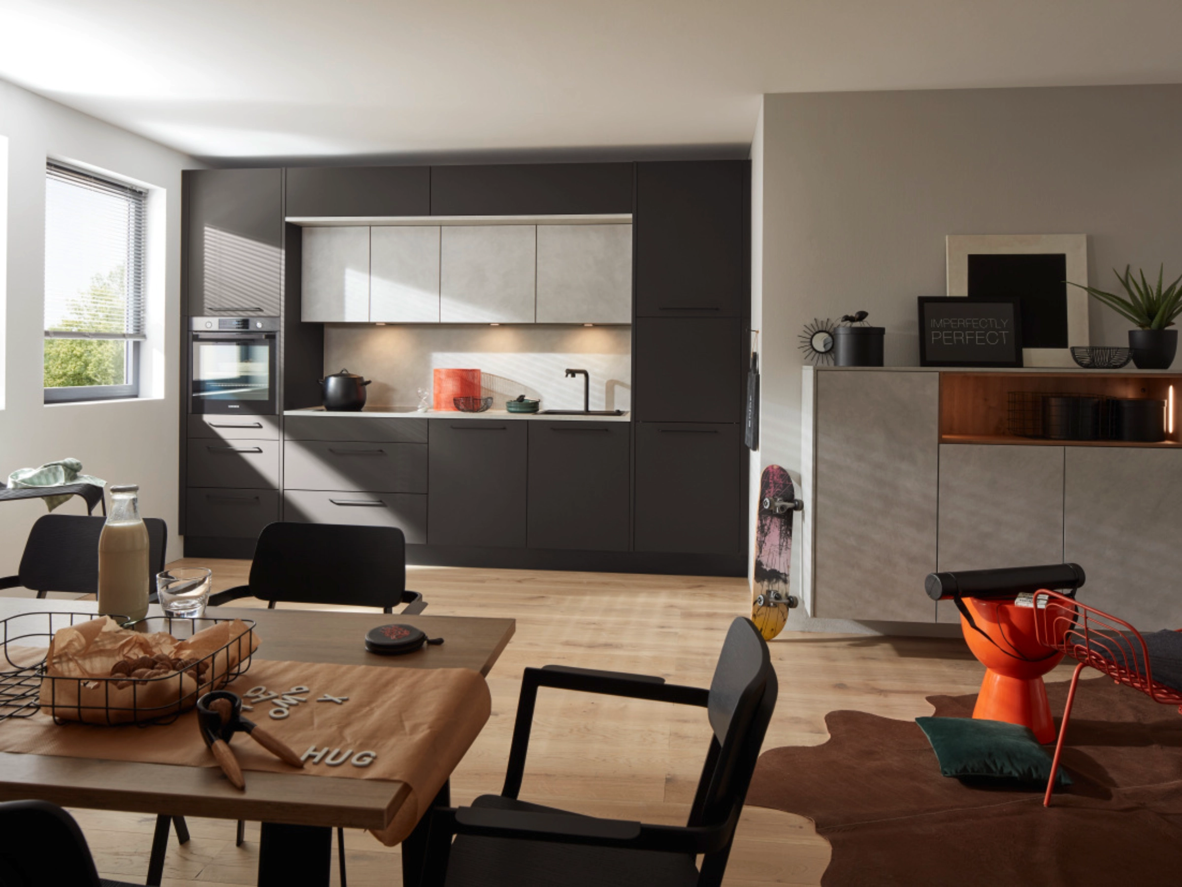 Cuisine moderne avec armoires sombres et table à manger, présentée par Nolte Kitchen.