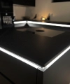 Cuisine moderne noire avec îlot éclairé, conçue par Nolte Kitchen.