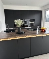A modern kitchen with dark cabinets and an island, decorated with flowers, by Nolte Kitchen.