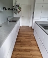 Eine moderne Küche mit weißen Schränken und Holzfußboden, Nolte Küchen.