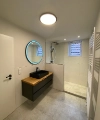 Salle de bain moderne avec lavabo noir et miroir rond éclairé, Nolte SPA.