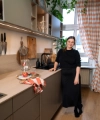 Dans la cuisine moderne Nolte, une femme se tient près du plan de travail avec une planche en bois et des verres.