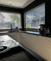 Une cuisine moderne avec des armoires blanches et de grandes fenêtres laissant entrer beaucoup de lumière. Nolte Kitchen.
