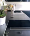 Eine moderne Küche mit schwarzer Arbeitsplatte und weißen Orchideen, Nolte Küchen.