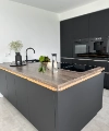 A modern kitchen with dark cabinets and wood accents, equipped by Nolte Kitchen.