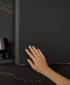 Een hand raakt een elegante zwarte keukenkast aan. Nolte Küchen.