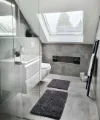 Modernes Badezimmer mit grauen Fliesen, Dachfenster und minimalistischer Einrichtung. Nolte SPA.