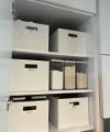 Ein geöffneter Schrank mit beschrifteten Vorratsboxen und -gläsern in einem Nolte Hauswirtschaftsraum.