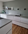 Eine moderne Küche mit weißen Schränken und Holzfußboden, präsentiert von Nolte Küchen.