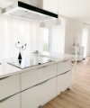Cuisine moderne avec îlot blanc et hotte, conçue par Nolte Kitchen.