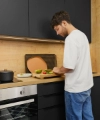 A man chopping vegetables in a modern kitchen with black cabinets. Nolte Kitchen.