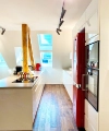 Une cuisine moderne avec des accents rouges et des éléments en bois, éclairée par des fenêtres de toit. Nolte Kitchen.