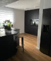 Eine moderne Küche mit dunklen Schränken und Holzfußboden von Nolte Küchen.