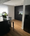 Une cuisine moderne avec des armoires sombres et un sol en bois de Nolte Kitchen.