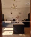 Cuisine moderne avec îlot et armoires sombres, éclairée par un lustre. Nolte Kitchen.