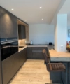 Cucina moderna con armadi scuri e accenti in legno, arredata da Nolte Kitchen.