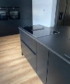 Cuisine moderne au design noir et parquet en bois, équipée de Nolte Kitchen.