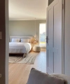 A modern bedroom with a double bed and carpet, seen through an open door. Nolte Living.